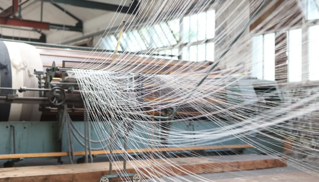 Feine Wollfäden werden in der Produktionshalle der FOXFORD Woollen Mills für den Webprozess vorbereitet